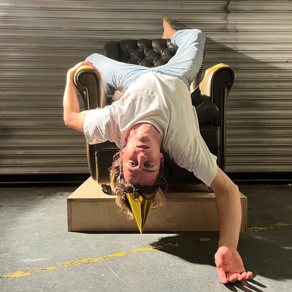 dancer in white tshirt laying head first from an armchair