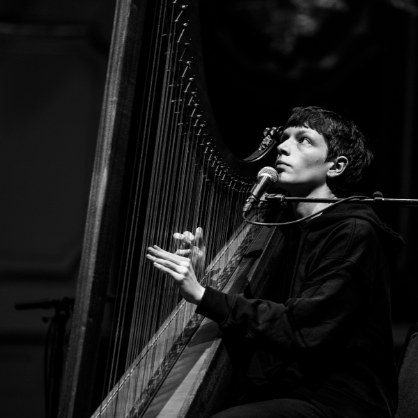 a black and white photo of Cerys playing their harp