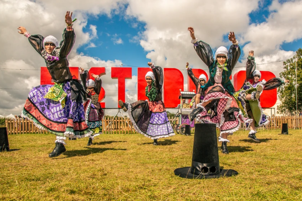 dancers in wild modern takes on traditional welsh costumes leaping in a field