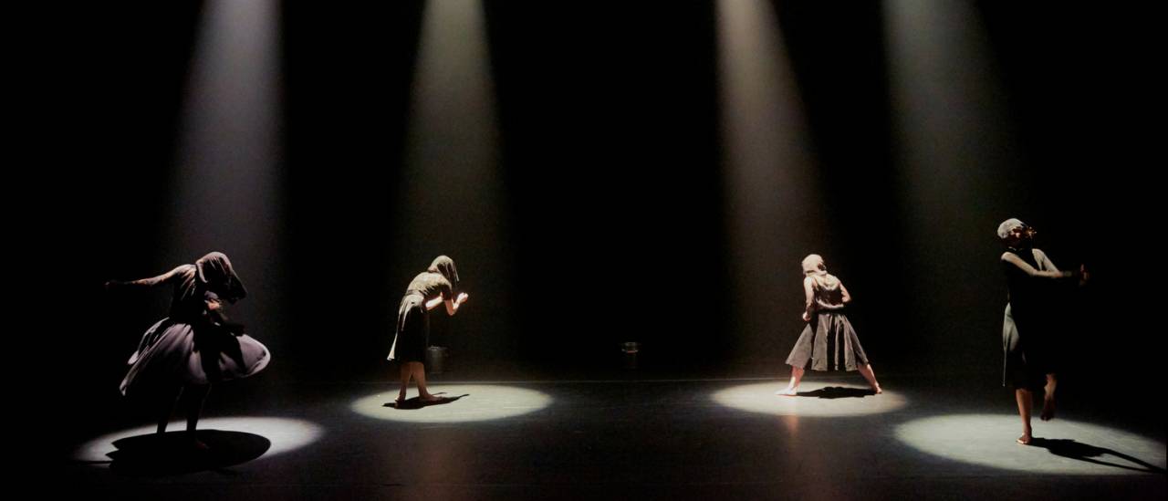 4 dancers each under a spotlight dressed in black