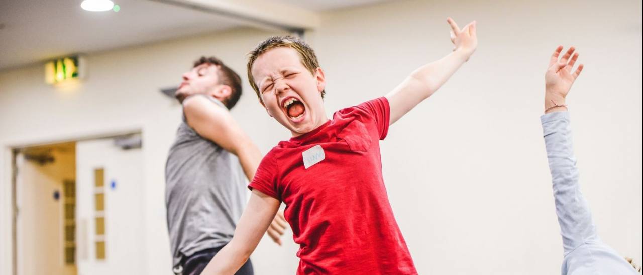 a boy stretching his arms out wide and his mouth