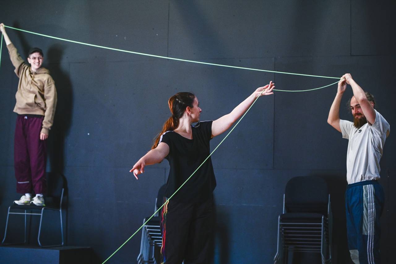 Artist and dancers holding long string at various levels