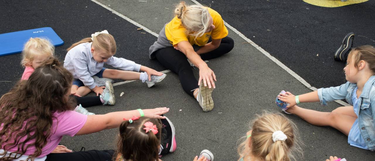 young people sat on floor stretching to touch their toes