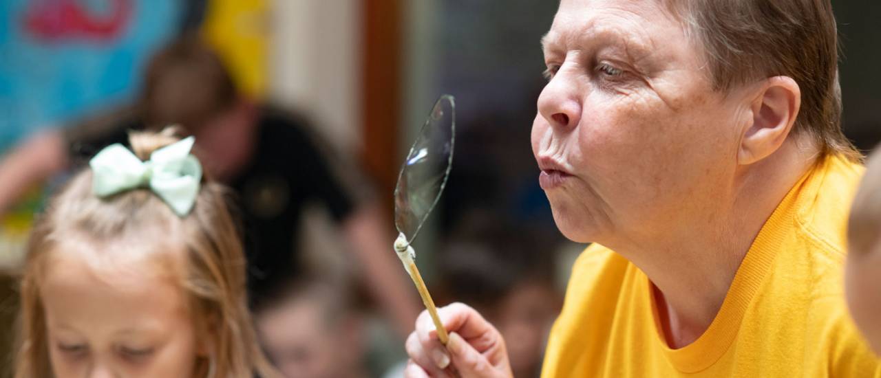 woman in yellow tshirt blowing a bubble