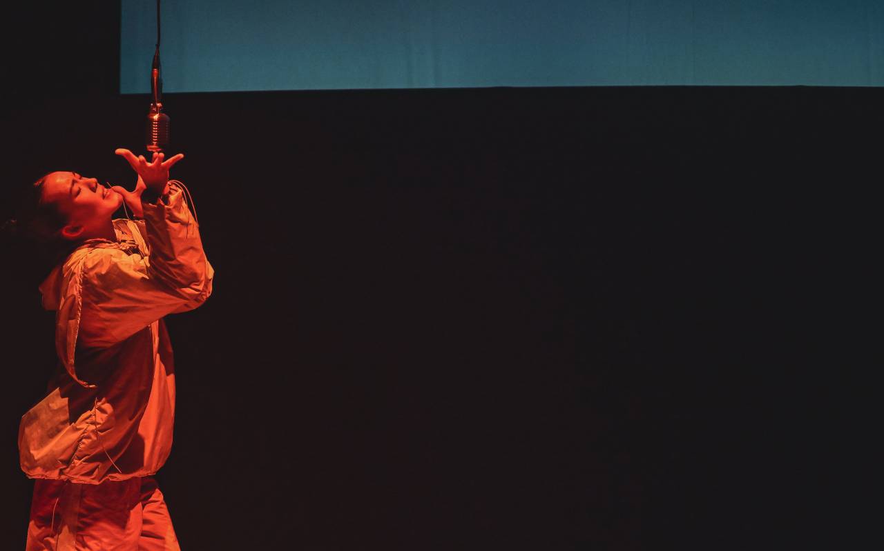 dancer singing into microphone under red light