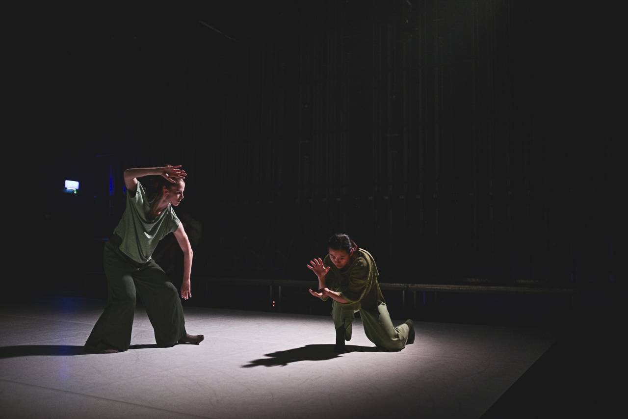 two dancers in soft light and green flowy outfits, looking as if they're casting spells