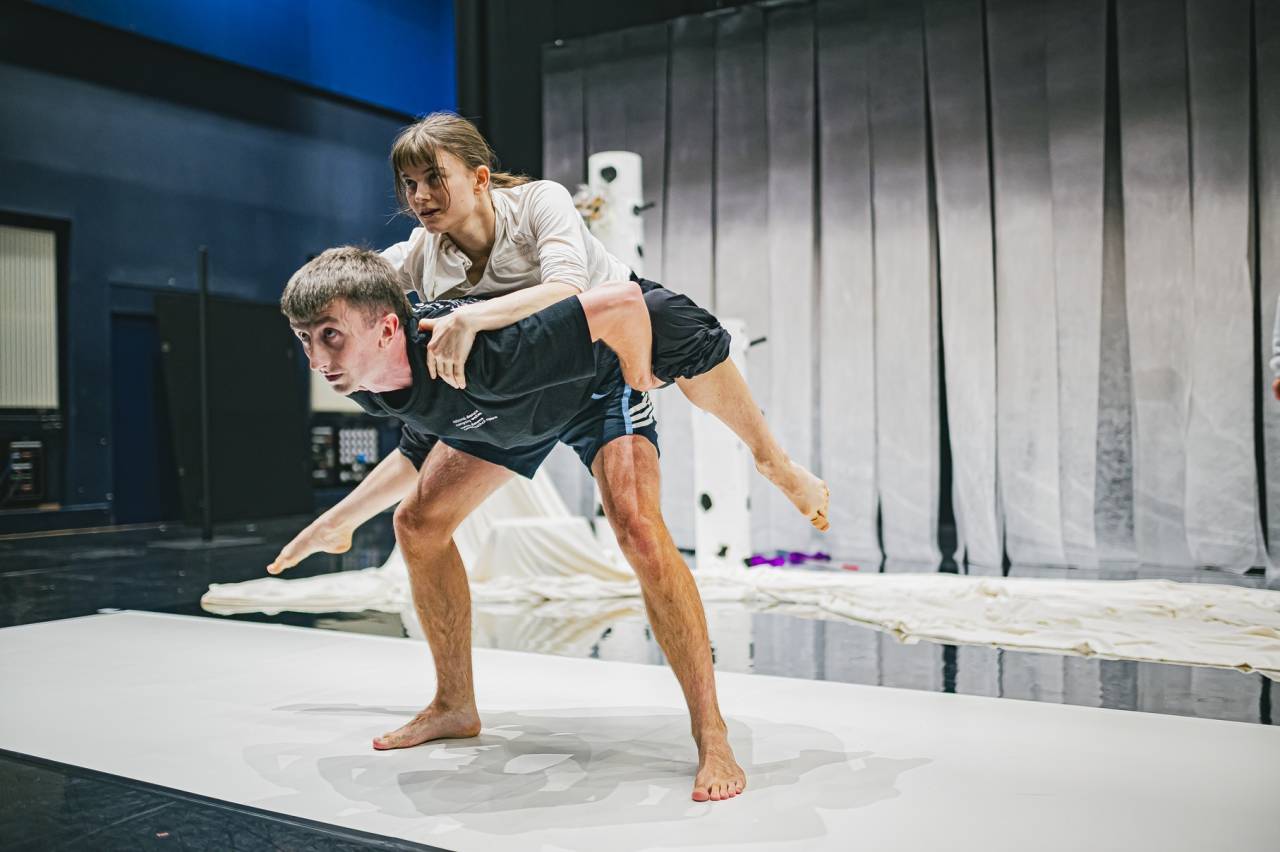 riz on another dancers back in rehearsal