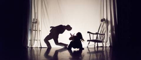 2 dancers, one as a silhouette behind a sheet and the second looking up from the floor