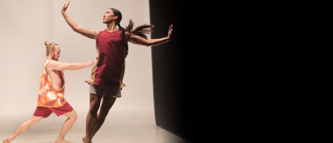 Dancer looks backwards with hands before her, in a gold and white sports outfit