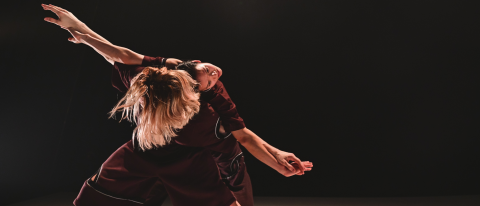 September image, two dancers entwined on the floor in black and white