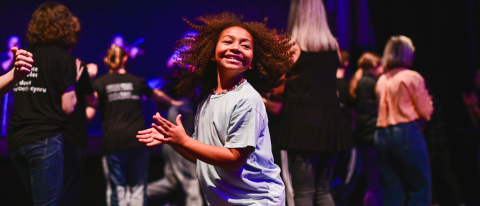 young person dancing and smiling, their hair flying out