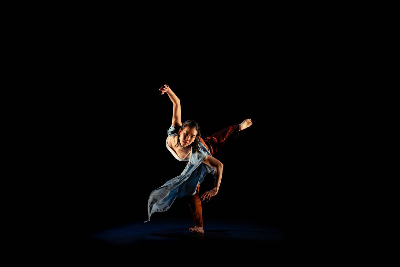faye is dressed as a salmon in Mabon, a large mask over her face as she slides across the floor, another dancer moving over her